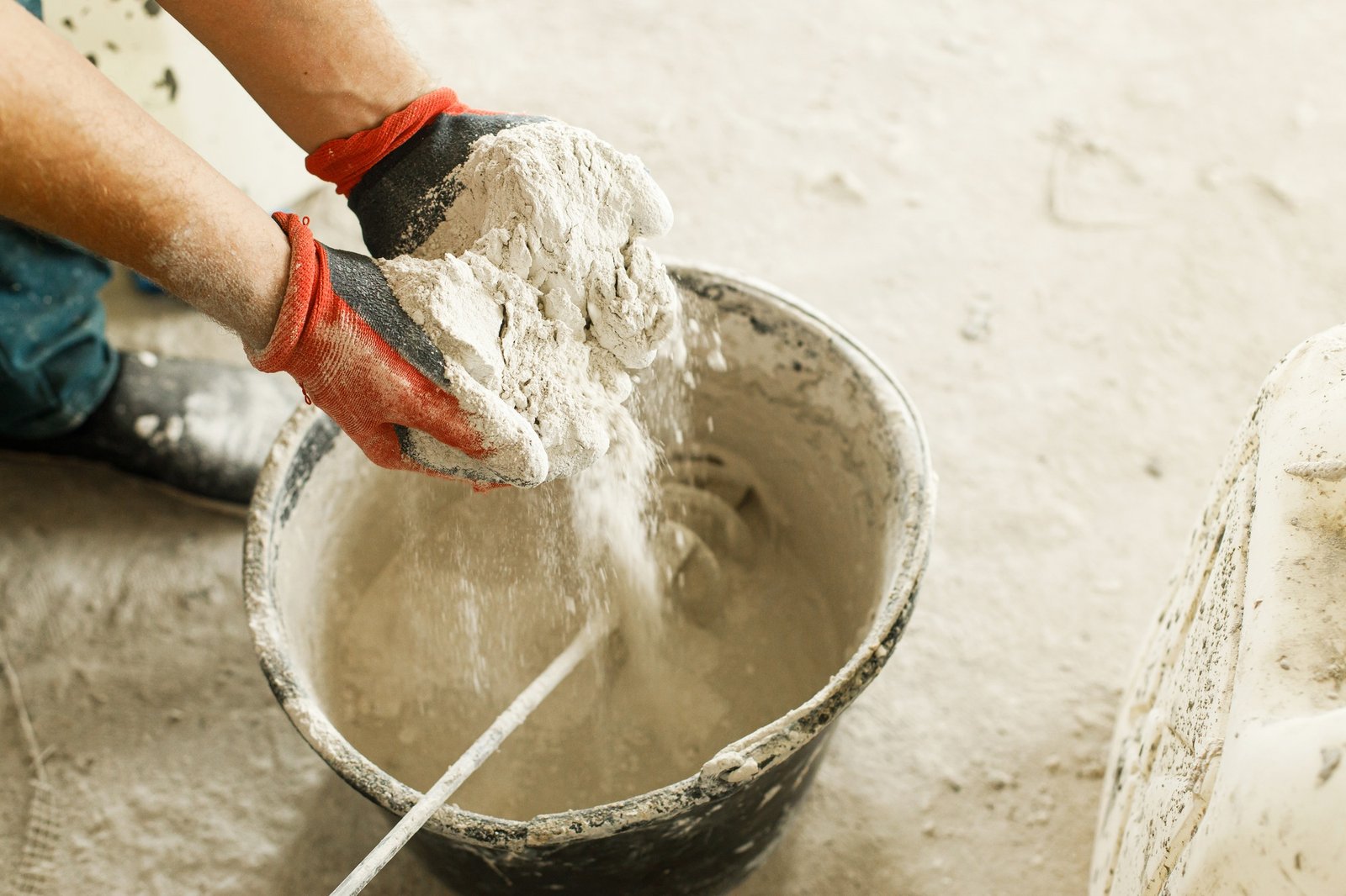 Worker mixing gypsum plaster with water for plastering walls